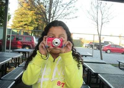 young student holding a pink Canon camera