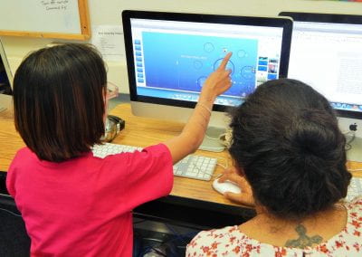 CLV mentor and mentee collaborate in front of a desktop computer monitor