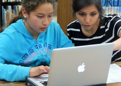 Corre LA Voz mentor helps Bayview student with editing on Mac laptop